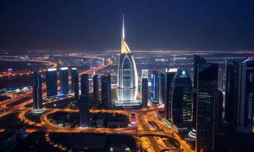 Aerial night view of Sheikh Zayed Road and Dubai skyline glowing with lights.